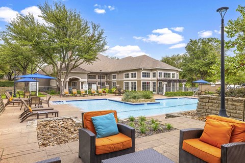 A poolside area with a house in the background.