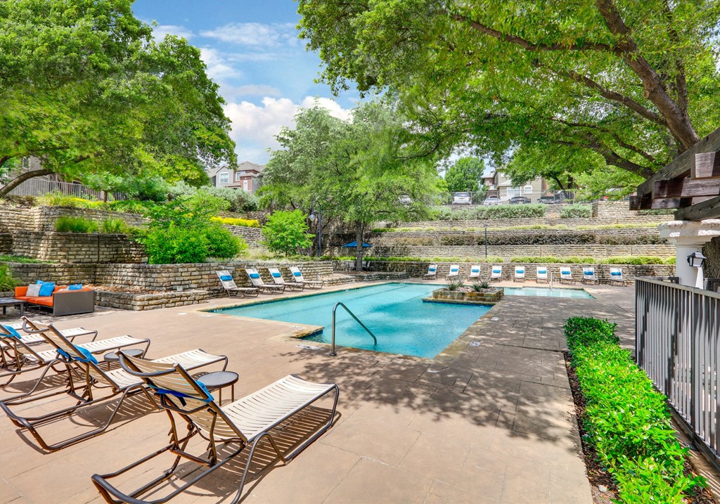 a swimming pool with chairs and trees in a courtyard