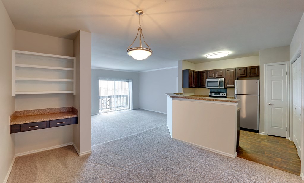 an empty kitchen and living room with an island and stainless steel appliances