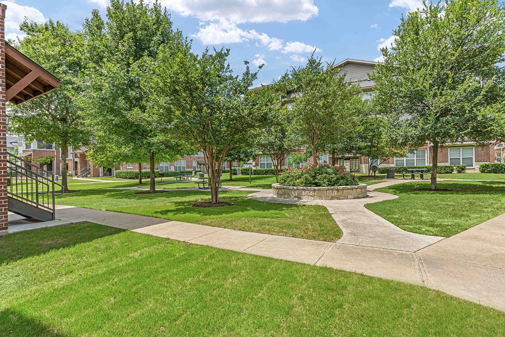 a park with trees and grass with a building in the background