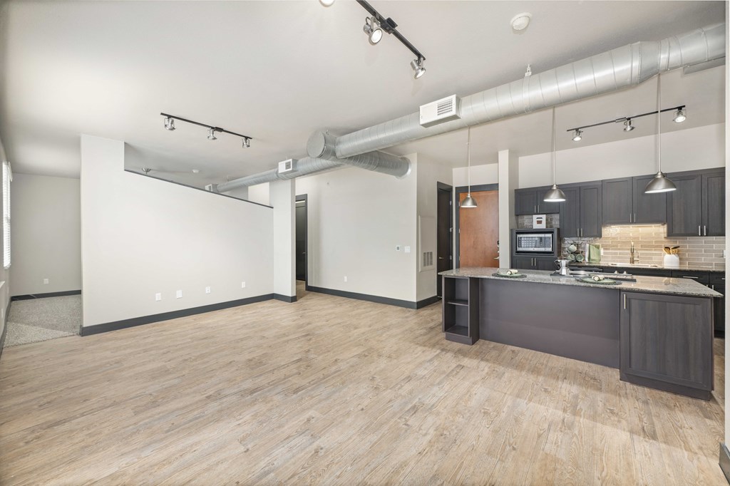 an open kitchen and living room with a kitchen island and wood floors