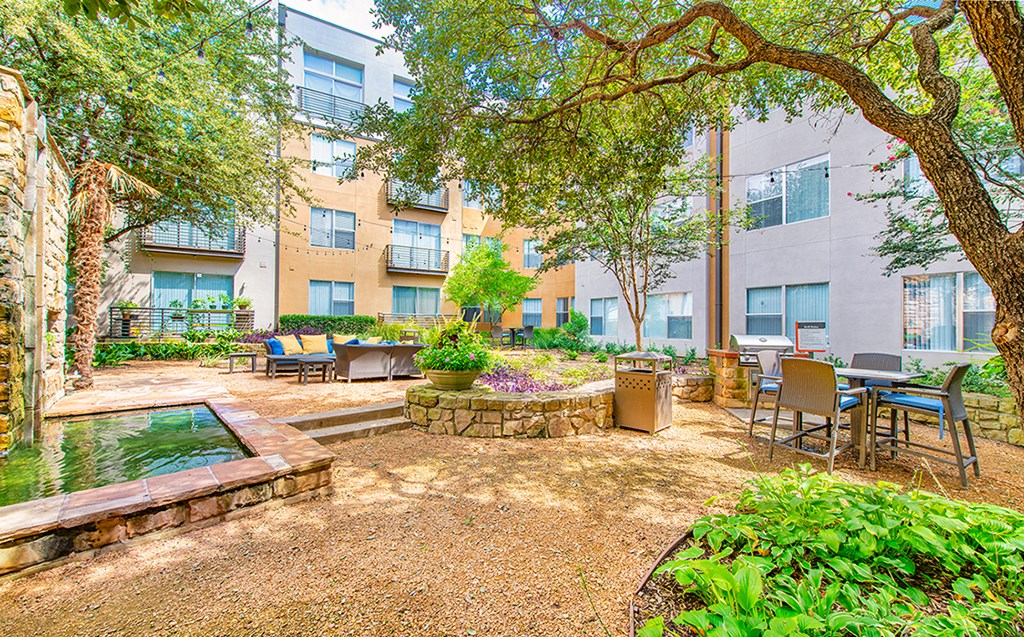 a courtyard with a fountain and tables and chairs in front of an apartment building