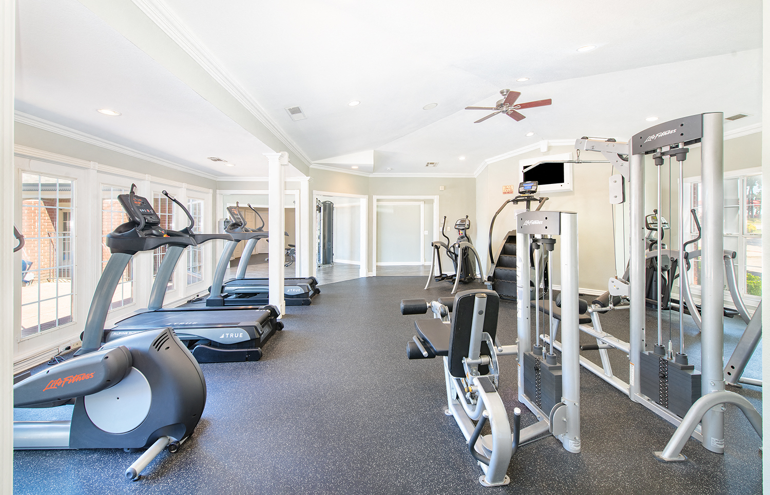 a gym with cardio machines and weights on the floor