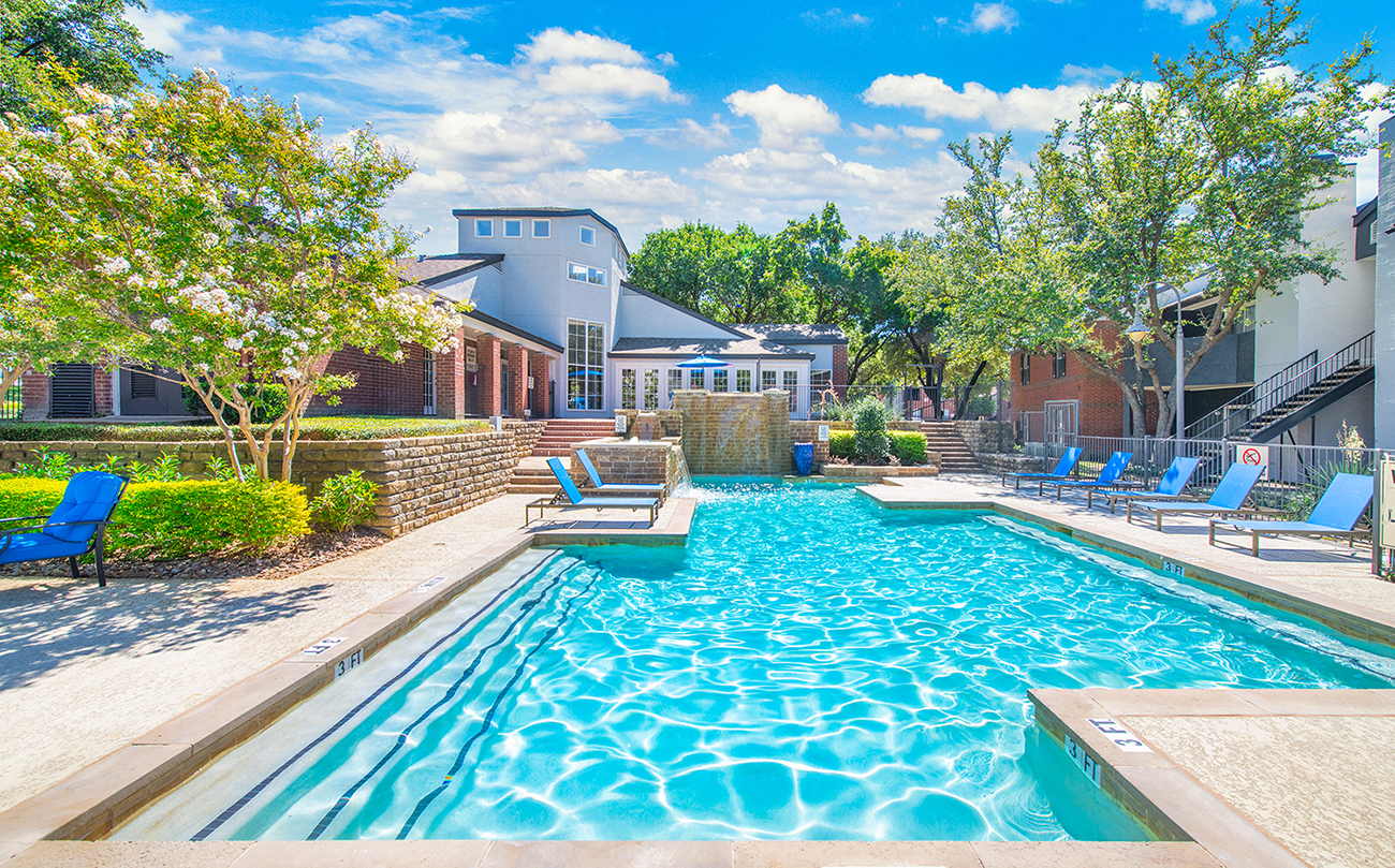 a swimming pool with blue chairs and a house in the background
