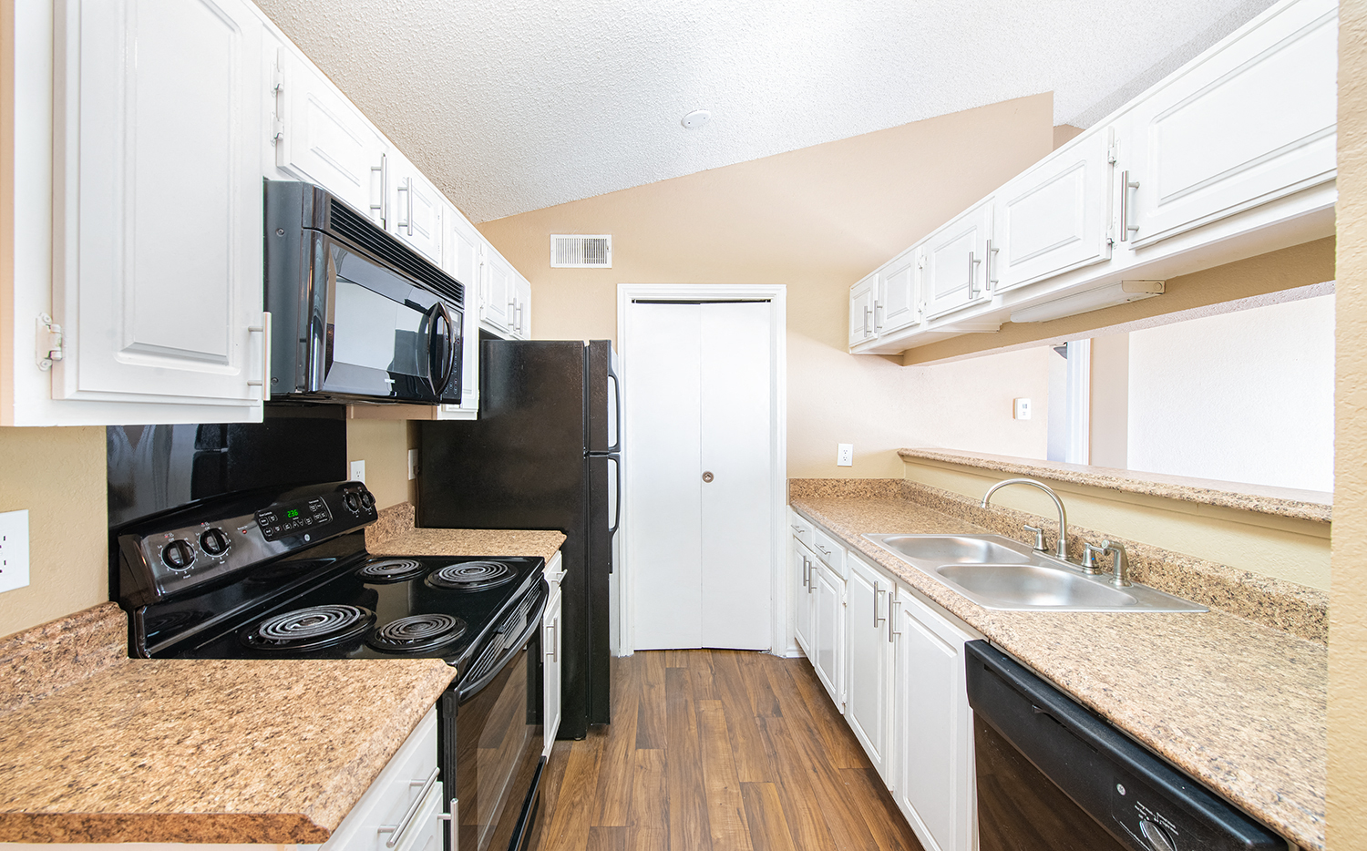 a kitchen with white cabinets and black appliances and granite counter tops