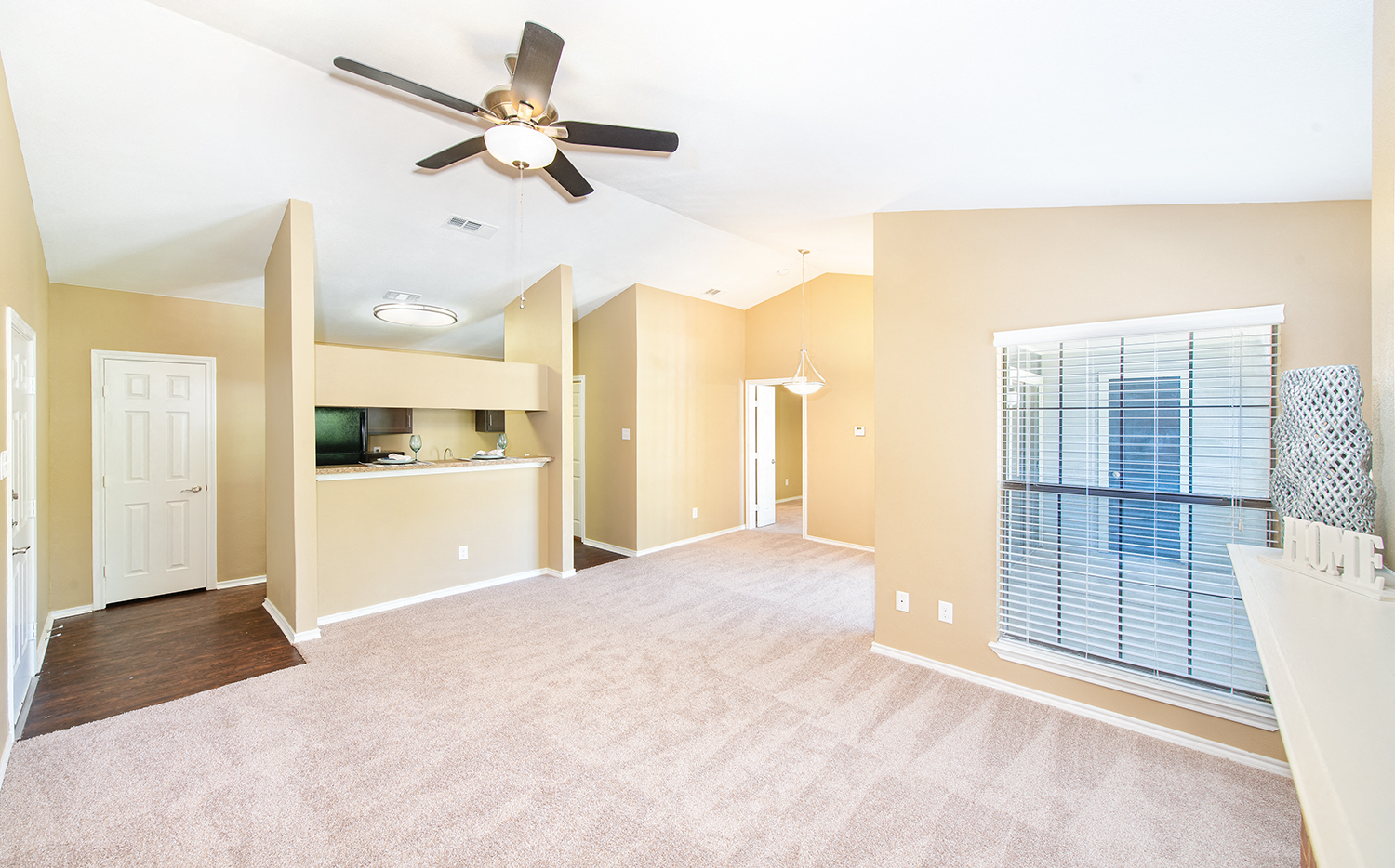 an empty living room with a ceiling fan and a window