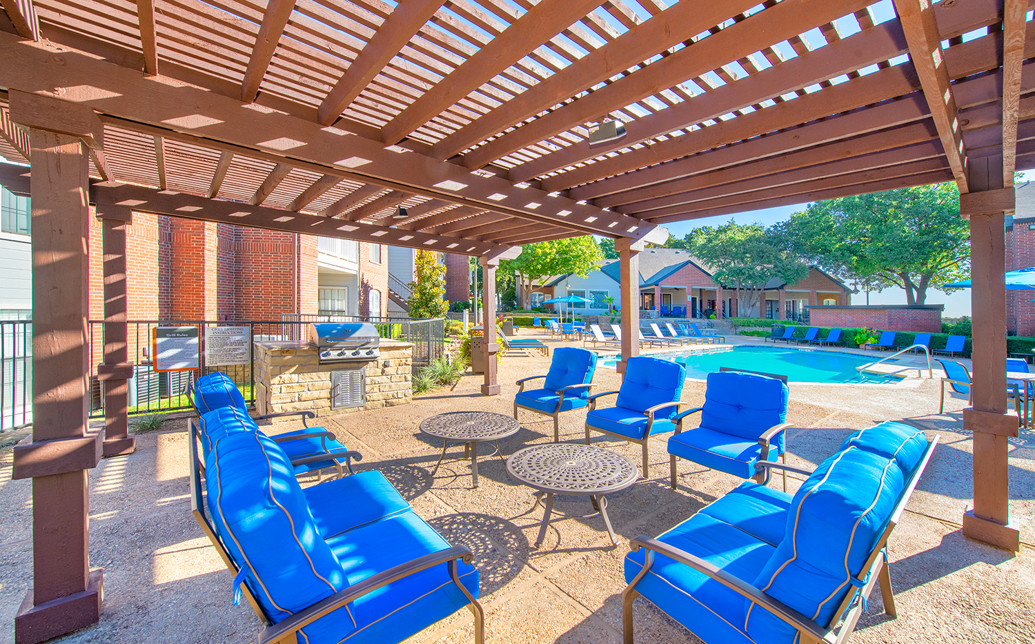 a covered patio with blue chairs and a swimming pool
