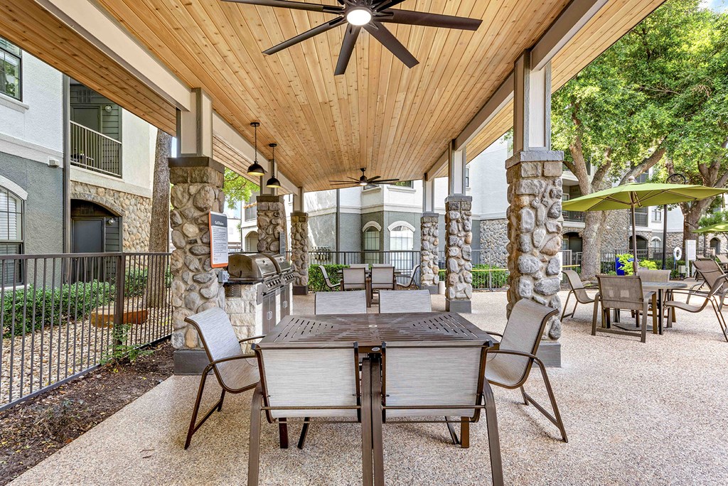 a covered patio with tables and chairs and a ceiling fan