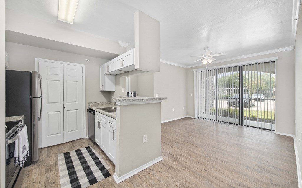 an open kitchen and living room with a door to a balcony