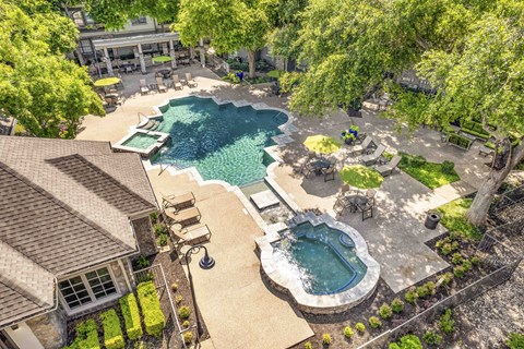an aerial view of a swimming pool and a resort style pool and yard with trees