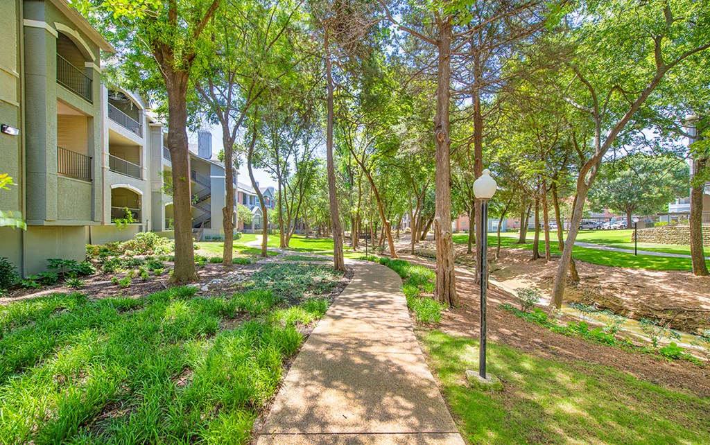 a pathway through the trees in front of an apartment building