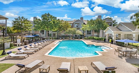 A large swimming pool surrounded by lounge chairs and umbrellas.