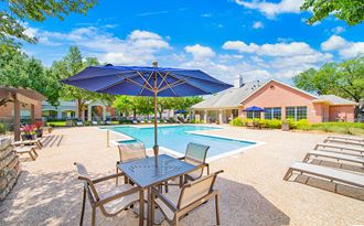 our resort style swimming pool is surrounded by patio furniture and umbrellas