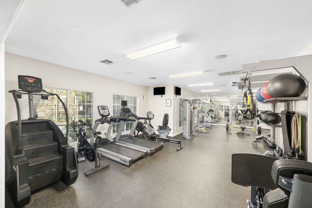 A gym with a variety of equipment including treadmills, weights, and exercise machines.