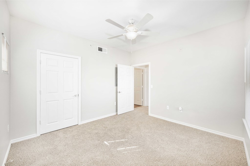 A room with a carpeted floor and a ceiling fan.