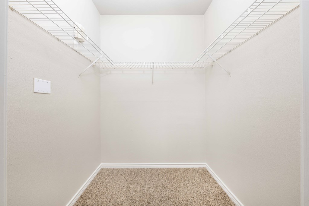 A white closet with a carpeted floor and a white door.