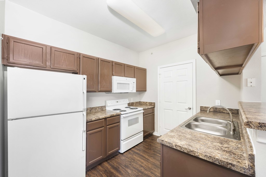 A kitchen with brown cabinets and a white refrigerator.