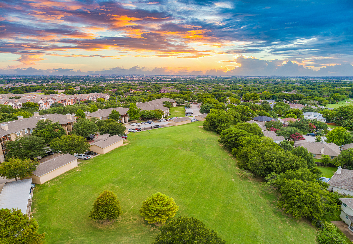 an aerial view of a neighborhood with houses and a green field