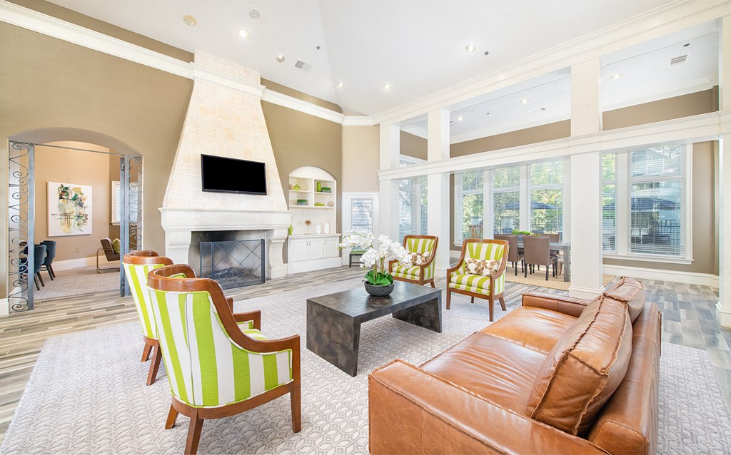 a living room with a leather couch and chairs and a fireplace