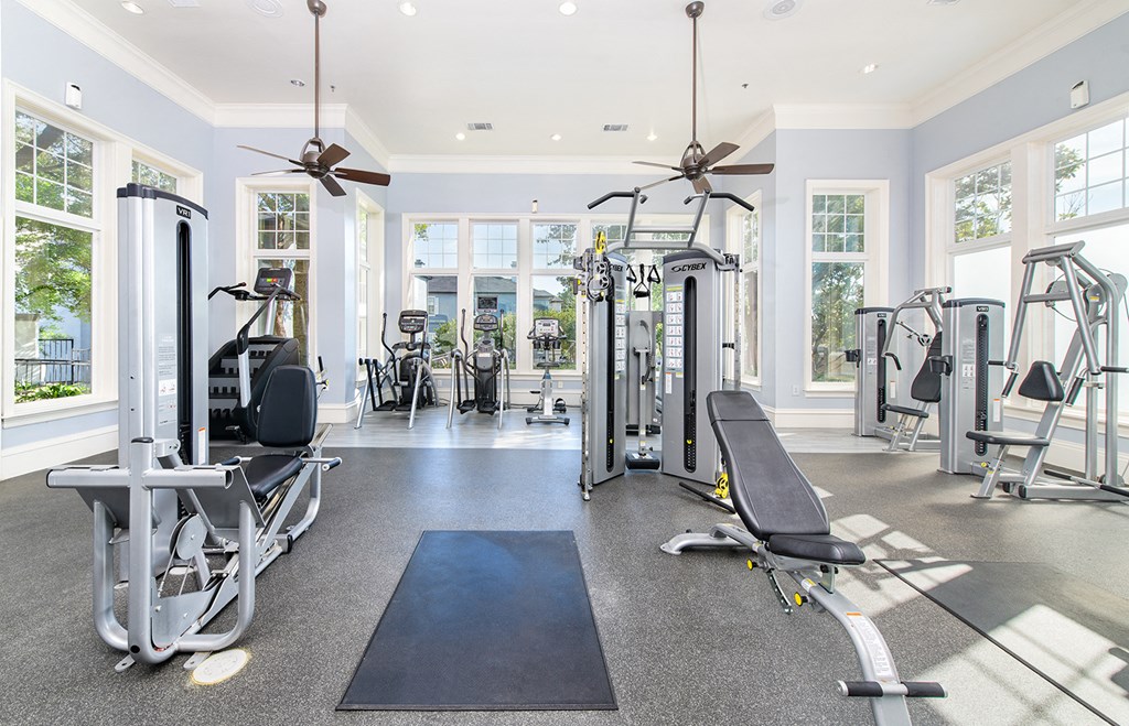 a gym with weights and cardio machines and ceiling fans