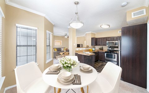 a dining room table with white chairs next to a kitchen