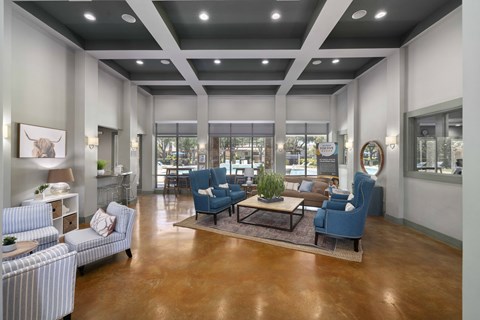 A spacious waiting area with blue chairs and a wooden floor.