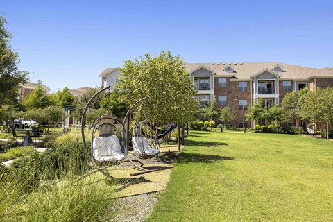 A sunny day at a park with a building in the background.