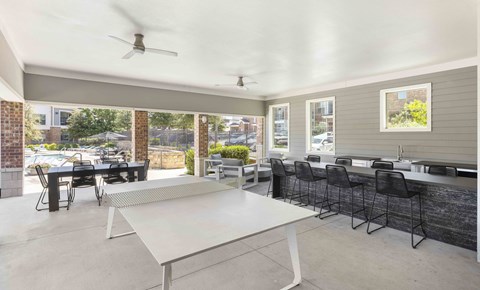 A white table is in the middle of a room with a ceiling fan and a brick wall.