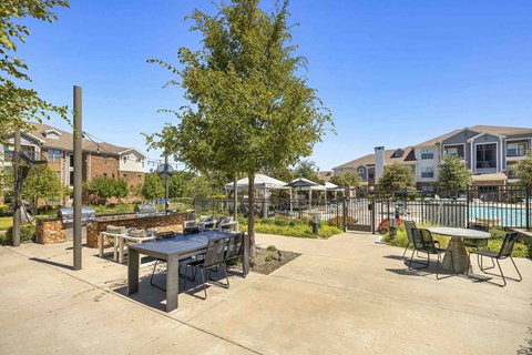 A large outdoor dining table surrounded by chairs is in the foreground of a residential area.