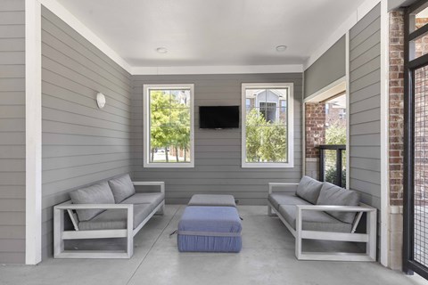 A grey patio with two couches and a bench.