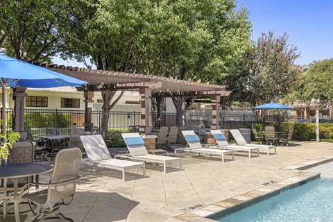 A pool area with chairs and a table.