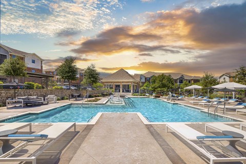 A large outdoor swimming pool surrounded by lounge chairs and umbrellas.