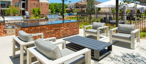 a patio with chairs and a table and a brick wall