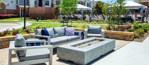 a patio with couches and chairs around a fire pit