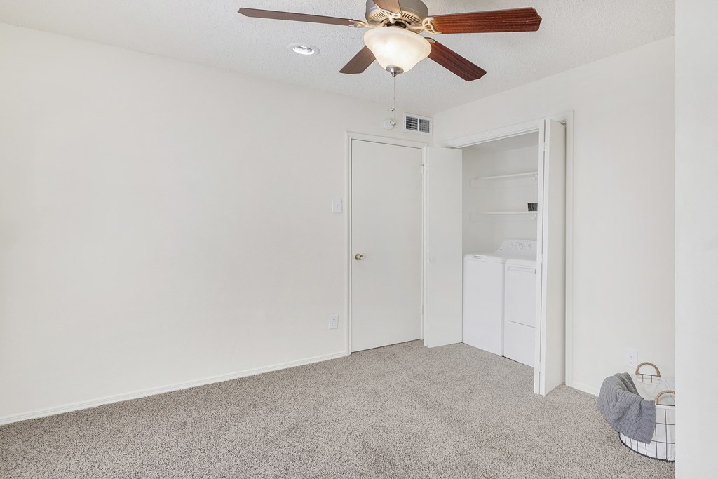 A room with a ceiling fan and carpeted floor.