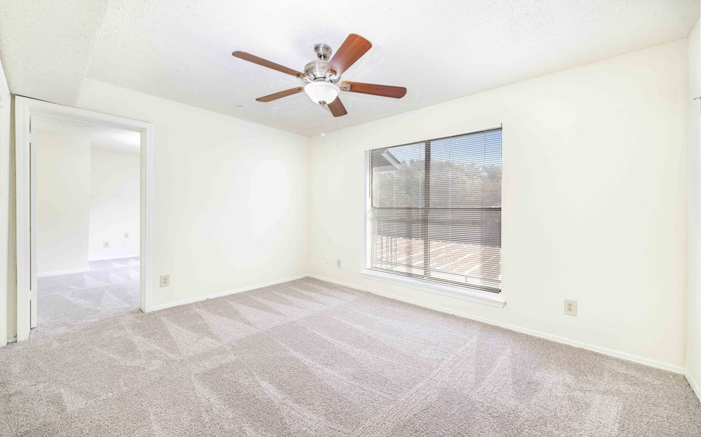 A room with a ceiling fan and a window with blinds.