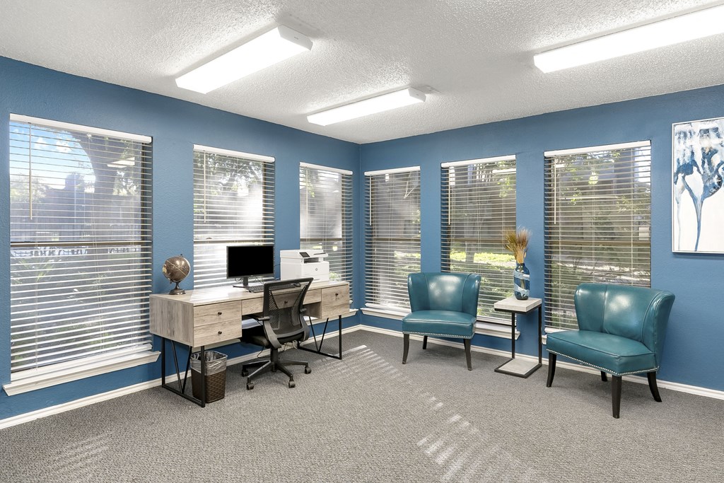 A room with a desk, chairs, and a computer.