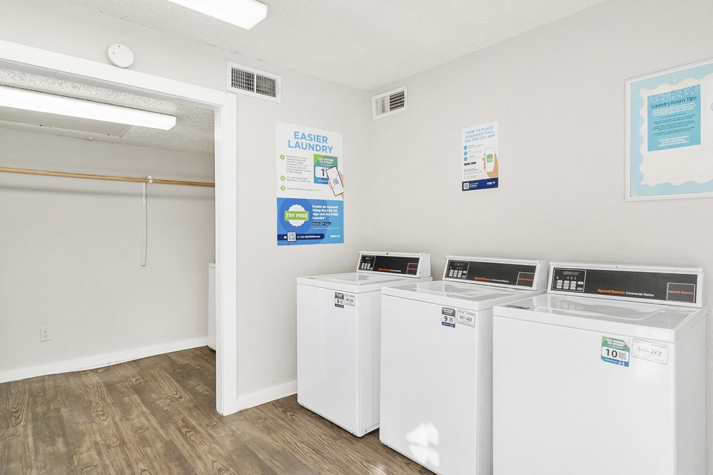 A laundry room with three washing machines and a sign that says "Easier Laundry".