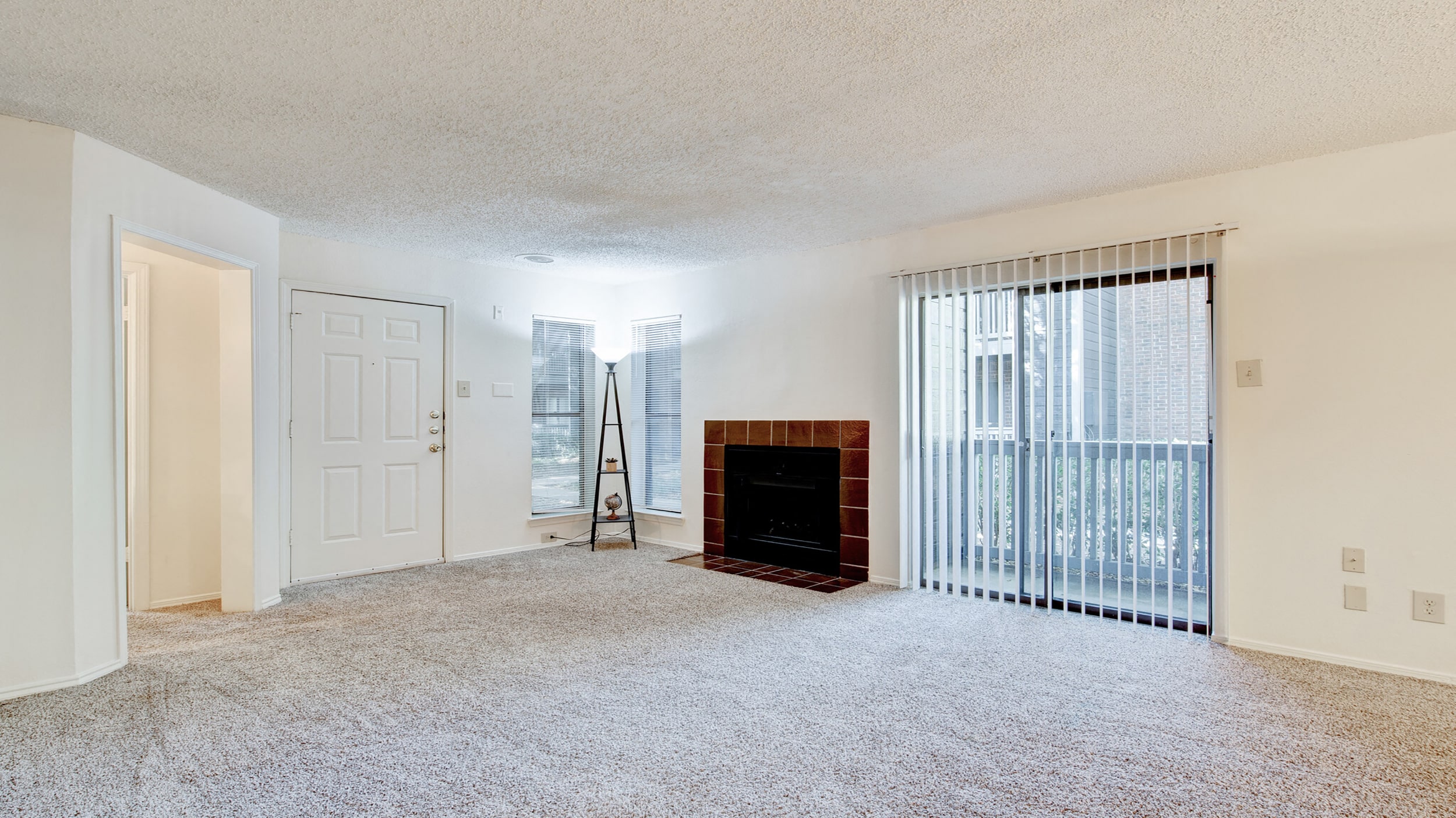 an empty living room with a fireplace and a sliding glass door
