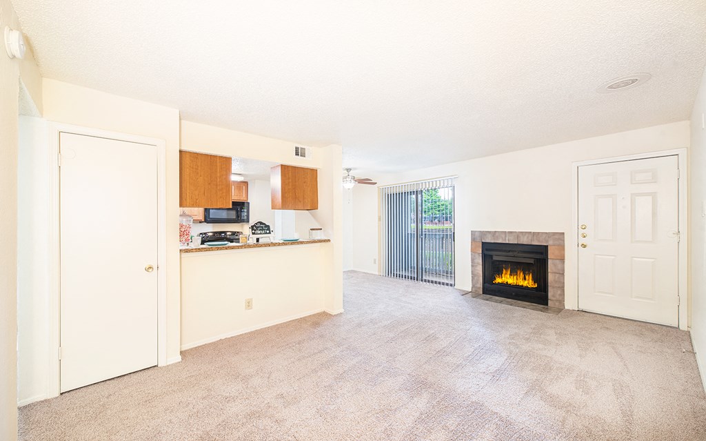 an empty living room with a fireplace and a kitchen