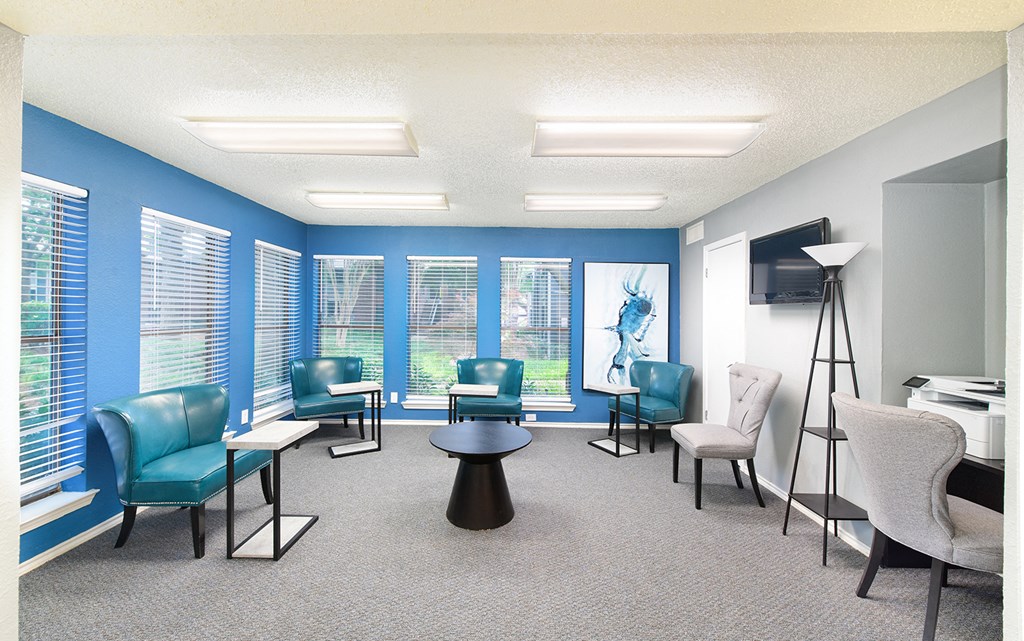 a waiting room with blue chairs and a table and a television