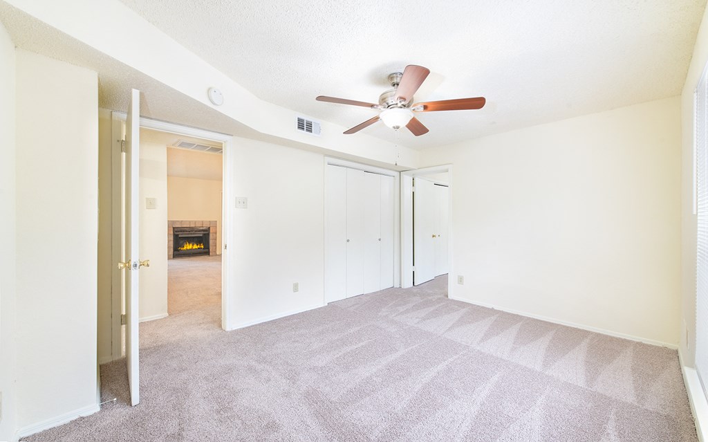 an empty living room with a ceiling fan and a closet