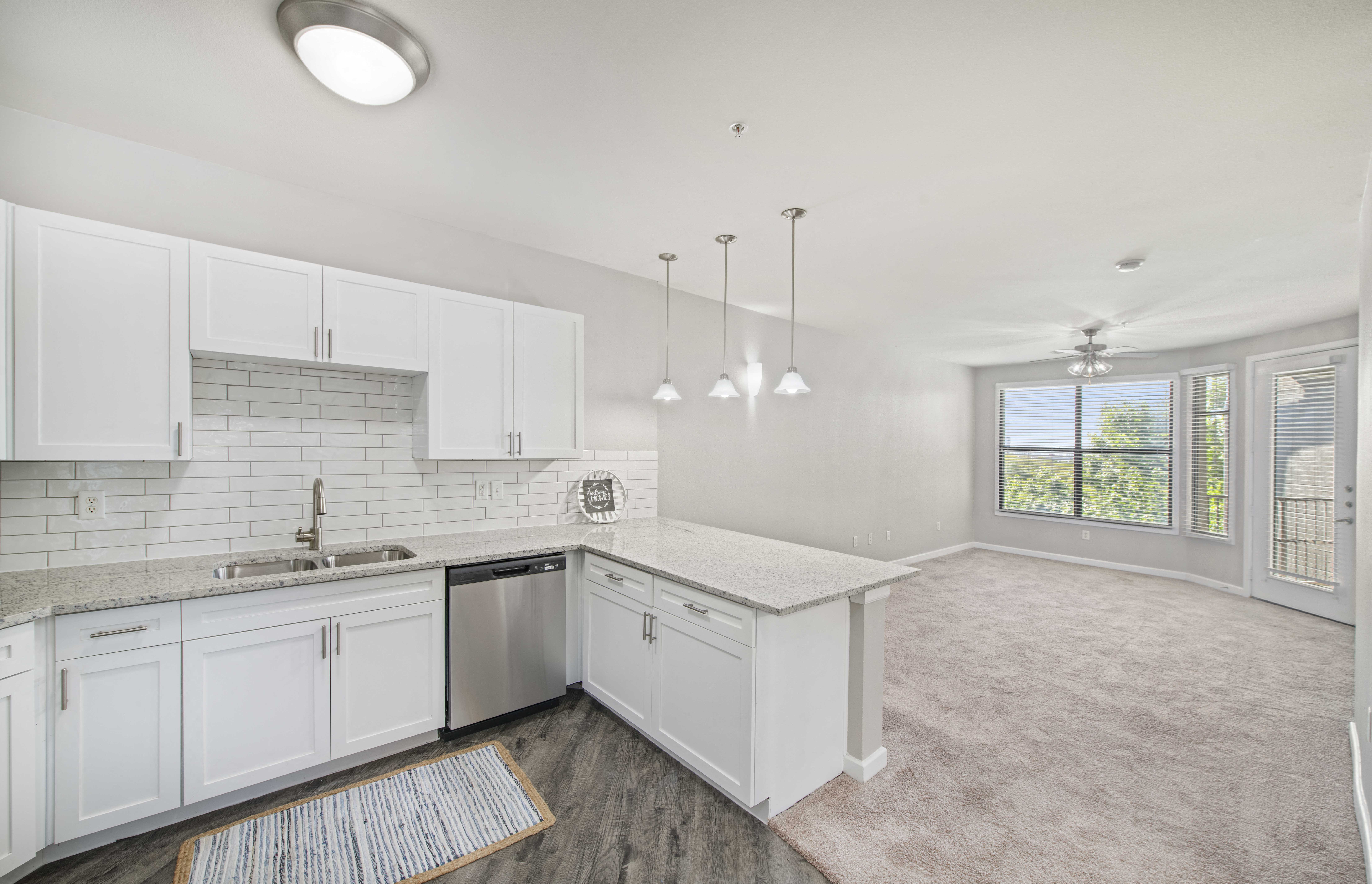 an empty kitchen with white cabinets and a large window