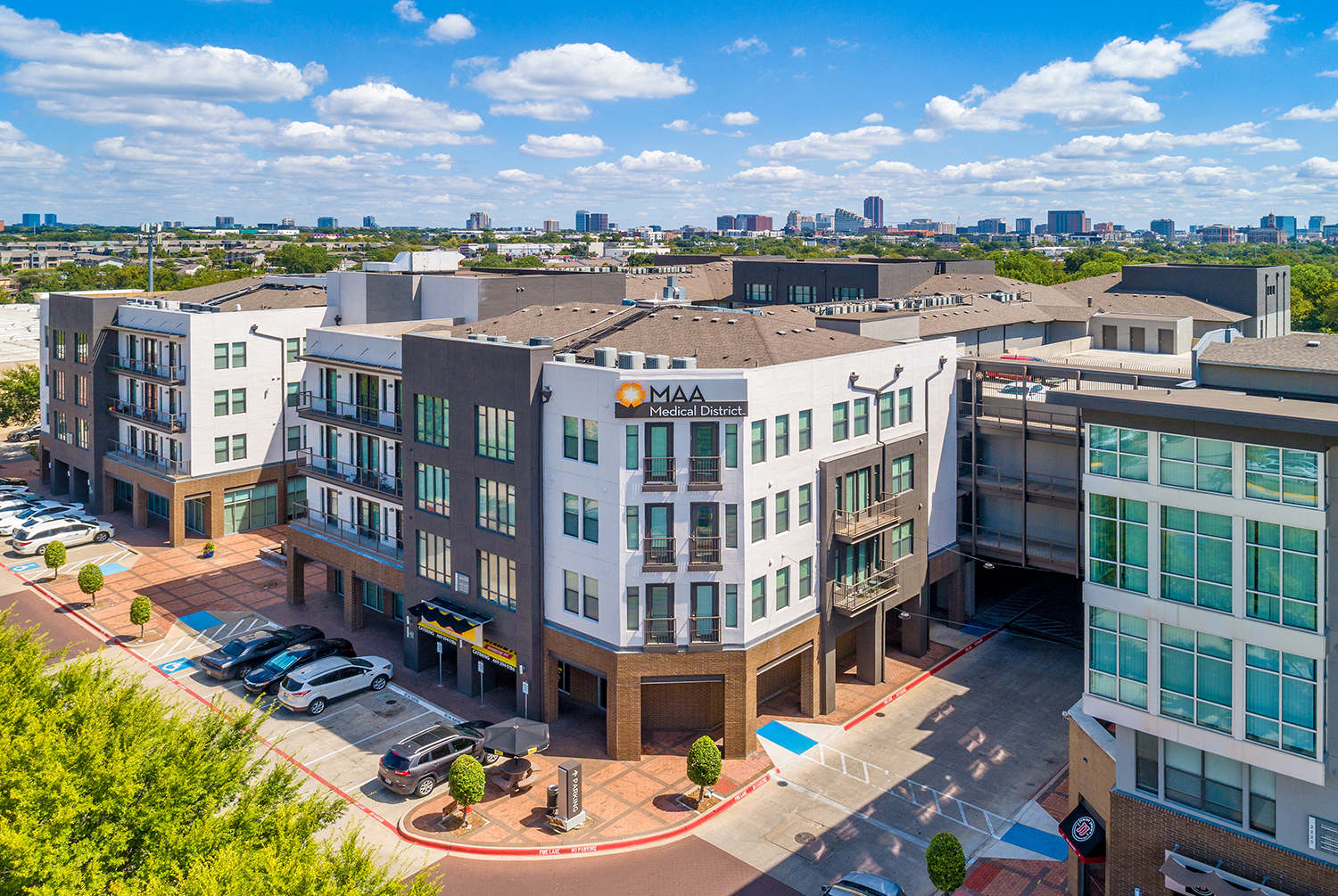 an aerial view of a building with a parking lot and a city in the background