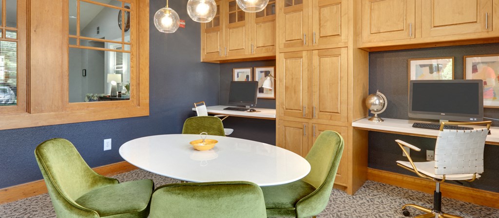 a home office with a white table and green chairs