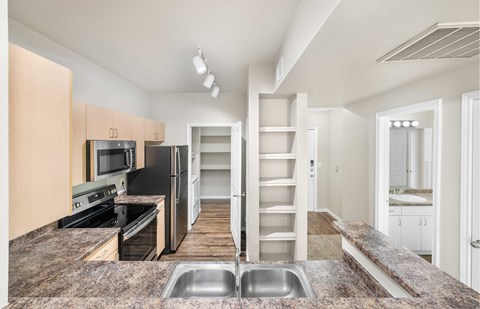 A kitchen with a refrigerator, microwave, oven, and sink.