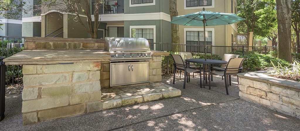 a backyard with a barbecue grill and a table and chairs