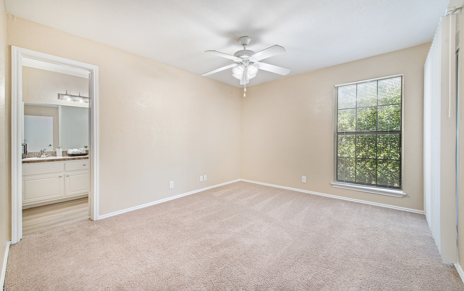 an empty living room with a ceiling fan and a window