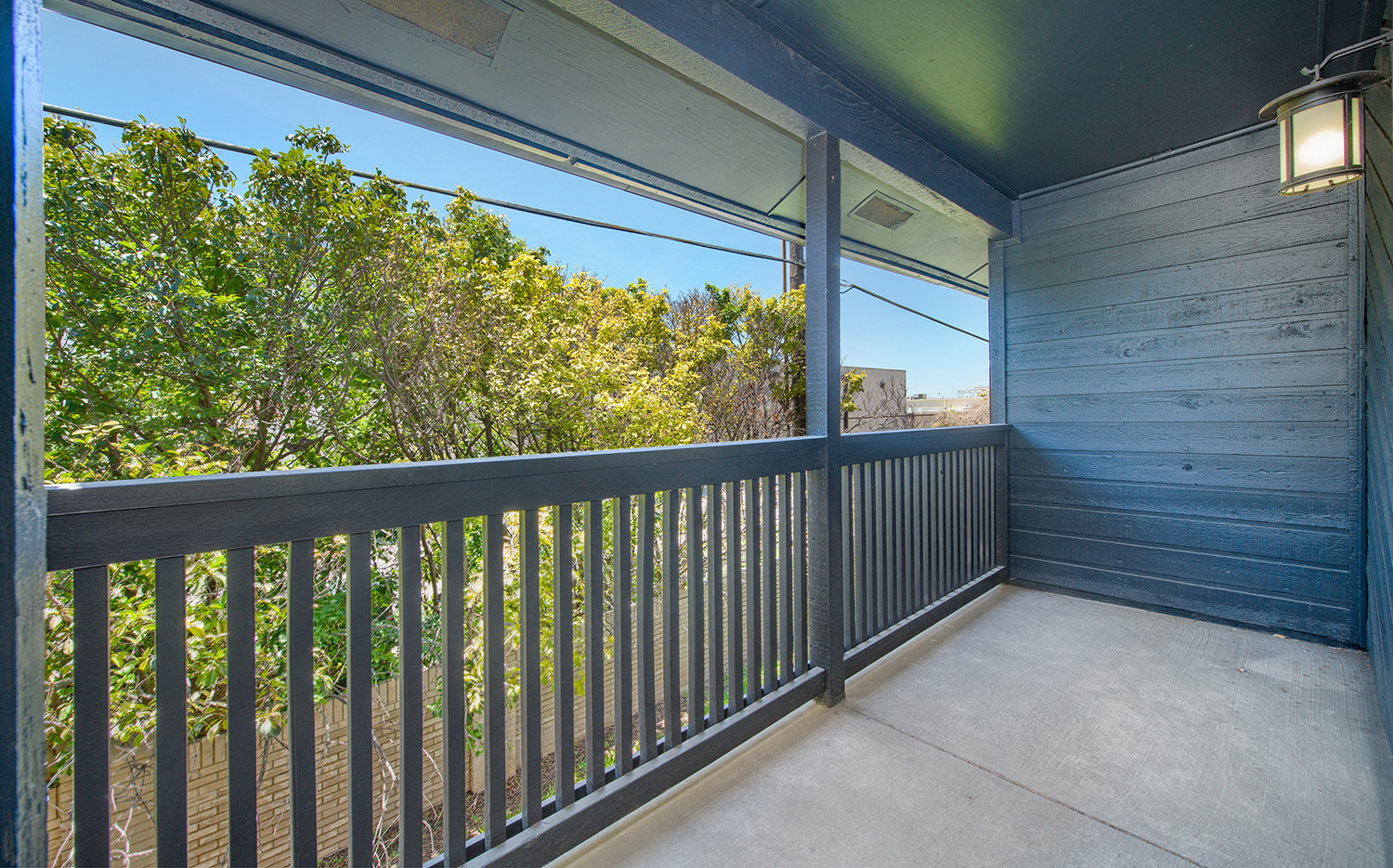 a balcony with a view of trees and a blue sky