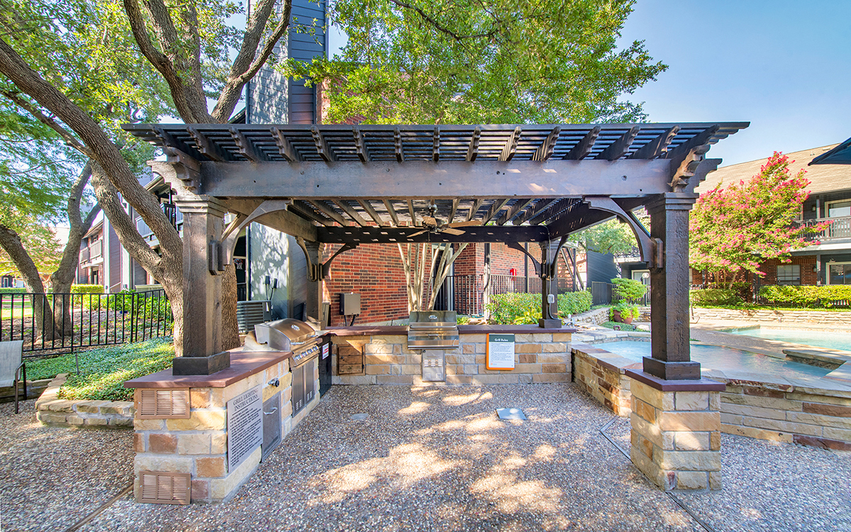 a stone patio with a pergola and a fountain